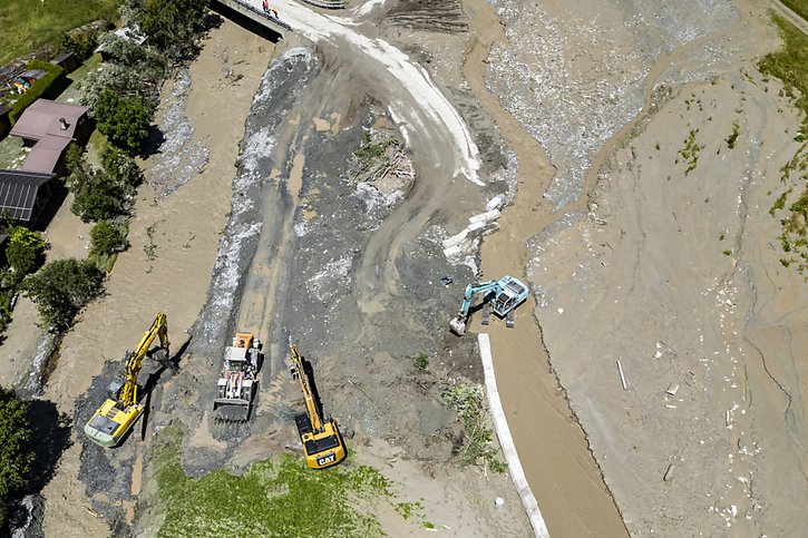 Des ouvriers avec des pelleteuses travaillent sur la coulée de lave torrentielle provenant du torrent du Fregnoley, à côté de la rivière la Dranse de Bagnes. © KEYSTONE/JEAN-CHRISTOPHE BOTT